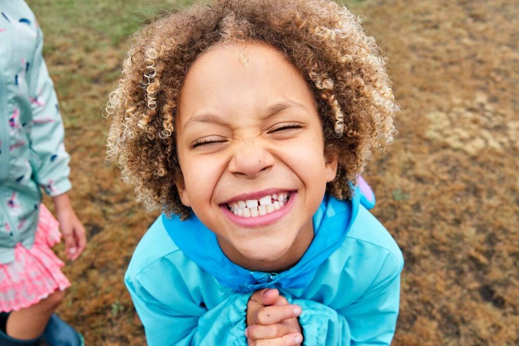 Girl looking up at camera pleasing to be allowed to take a picture to at Hayes Common in Bromley