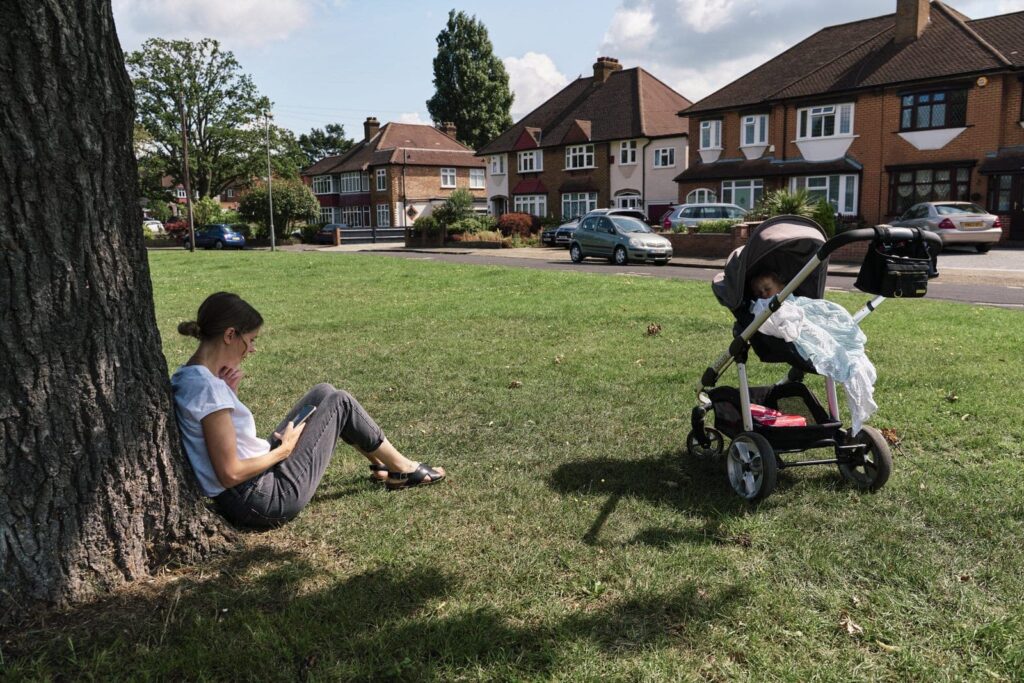 London parent listening to podcast while child sleeps in pram