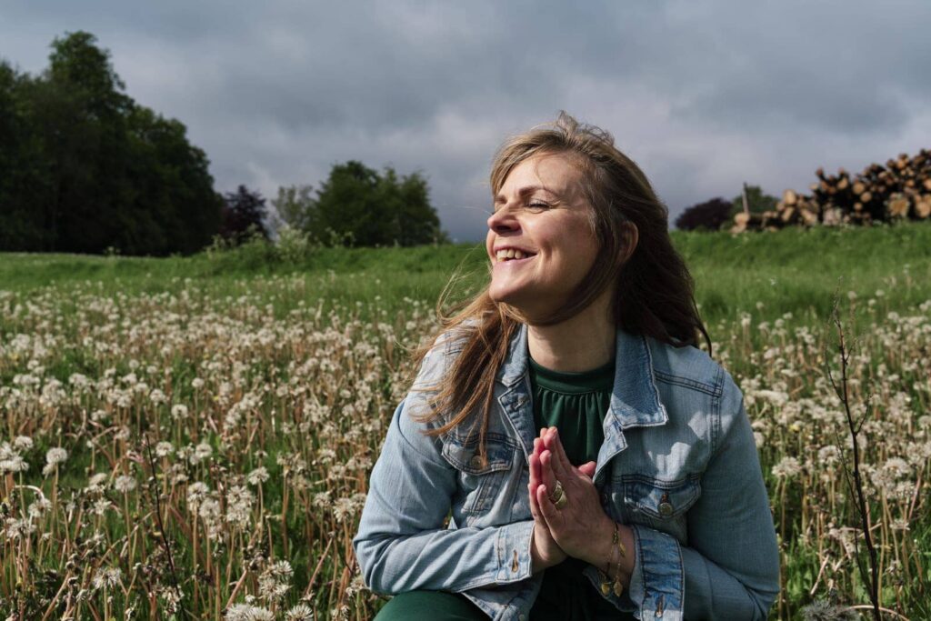 Woman sitting in a field enjoying the wind and sunshine at her brand photo location in nature. 