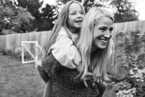 Photo of a mom carrying her child on her back during a family photography session in Reigate near London.