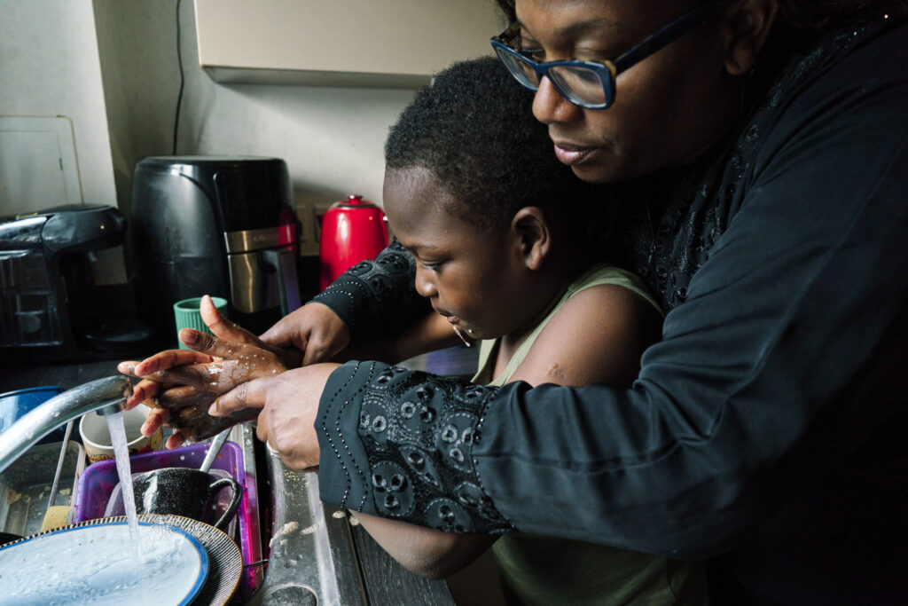 Mother washing the hands of her autistic son during a documentary family photo session in London