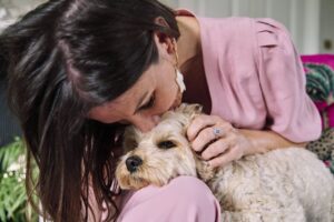 Woman kissing her prop which is a dog during a professional portrait session.