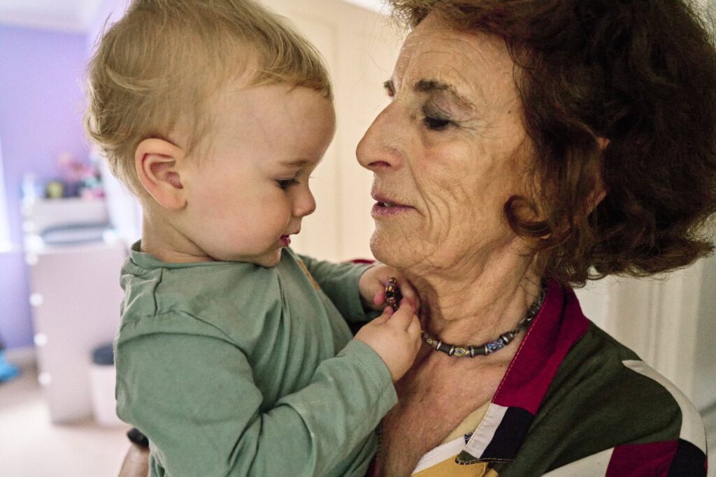 A boy looking at is grandmother's necklace during a family photo session and how much the photo session costs. 