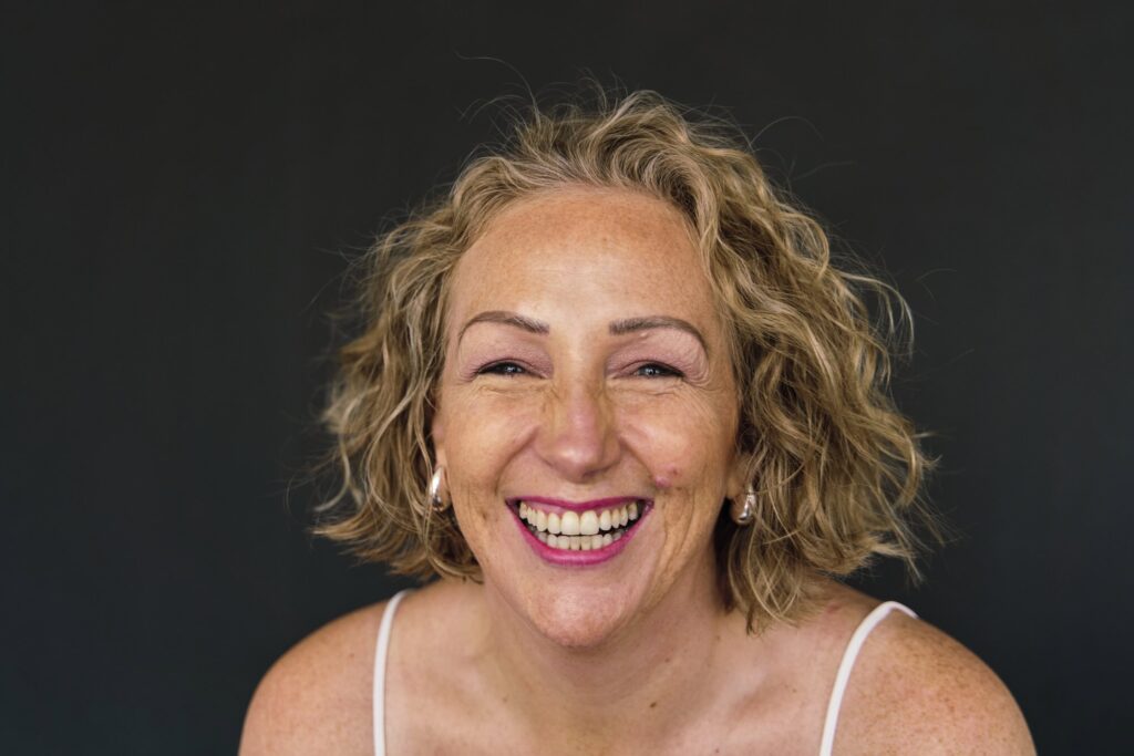 Natural headshot of a woman entrepreneur in London branding session, showing unretouched skin and a very big happy laugh that's real. 